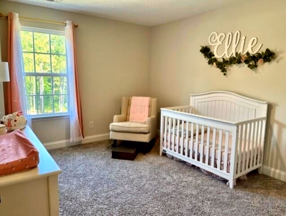 Nursery with plush carpet, large window, and soft natural light