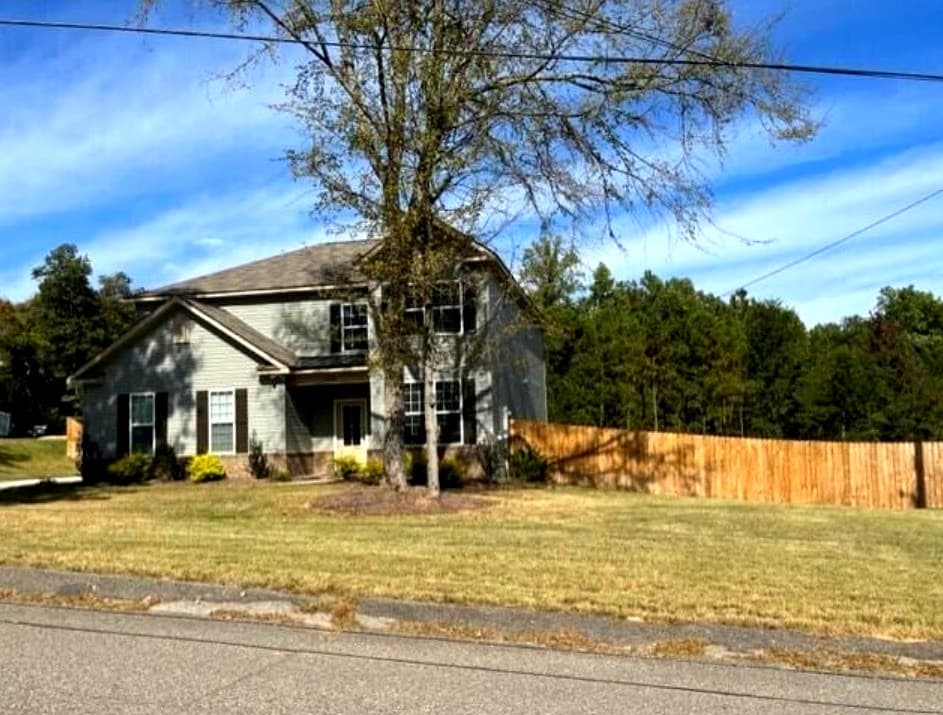 Side view of the home with fenced yard and mature shade trees