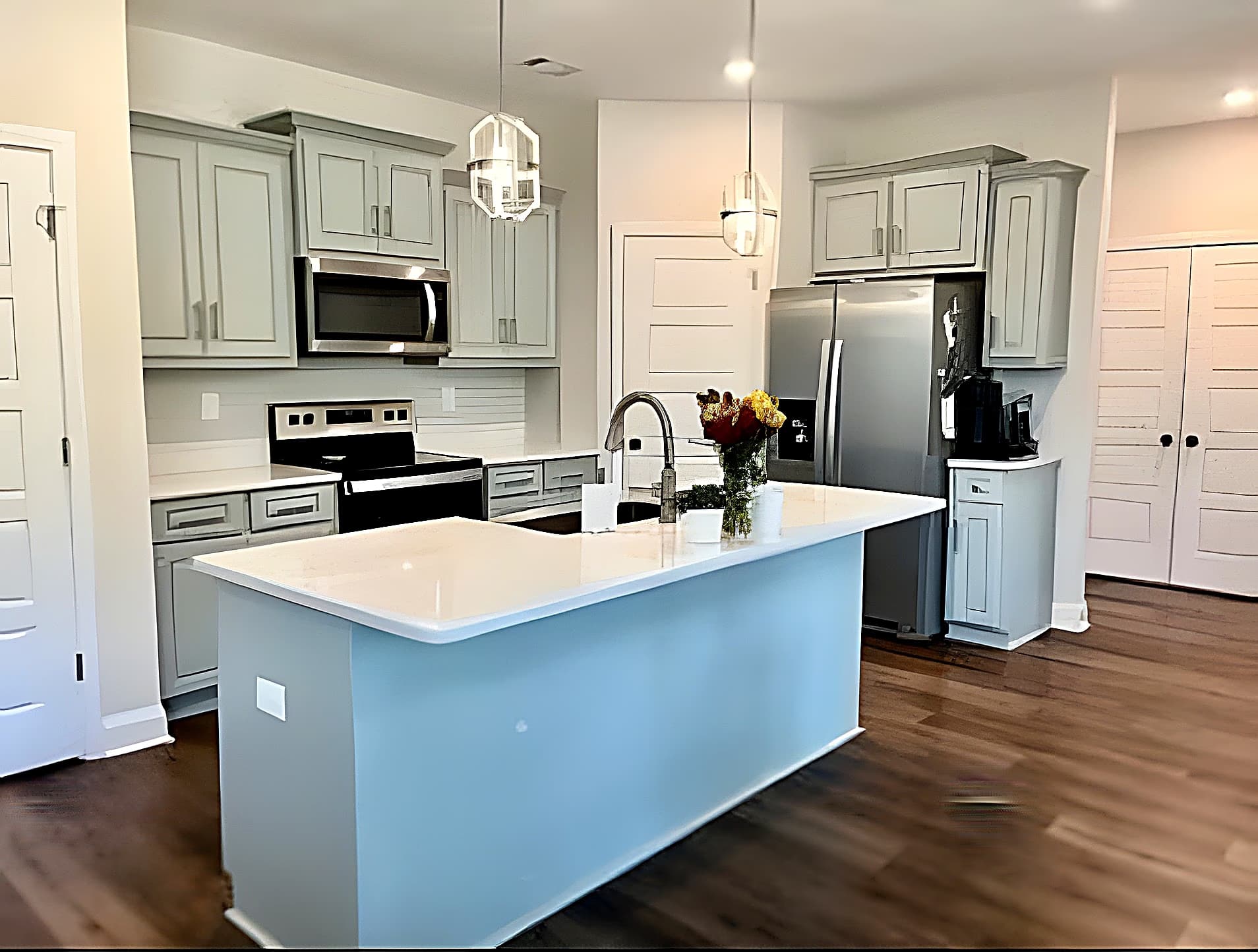Kitchen with quartz island, stainless appliances, and pendant lighting
