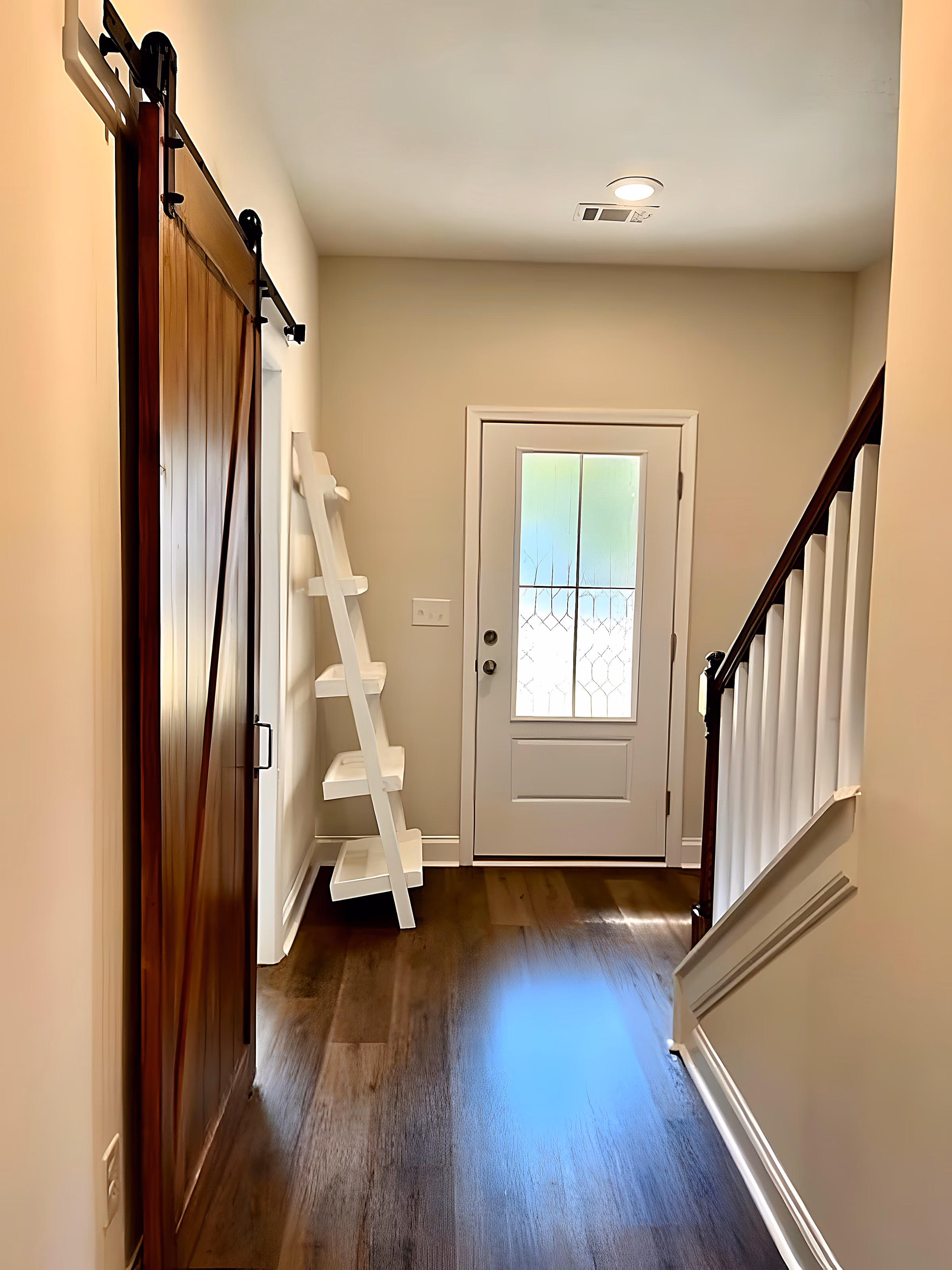 Foyer entry with barn door, stair rail, and glass-paneled front door