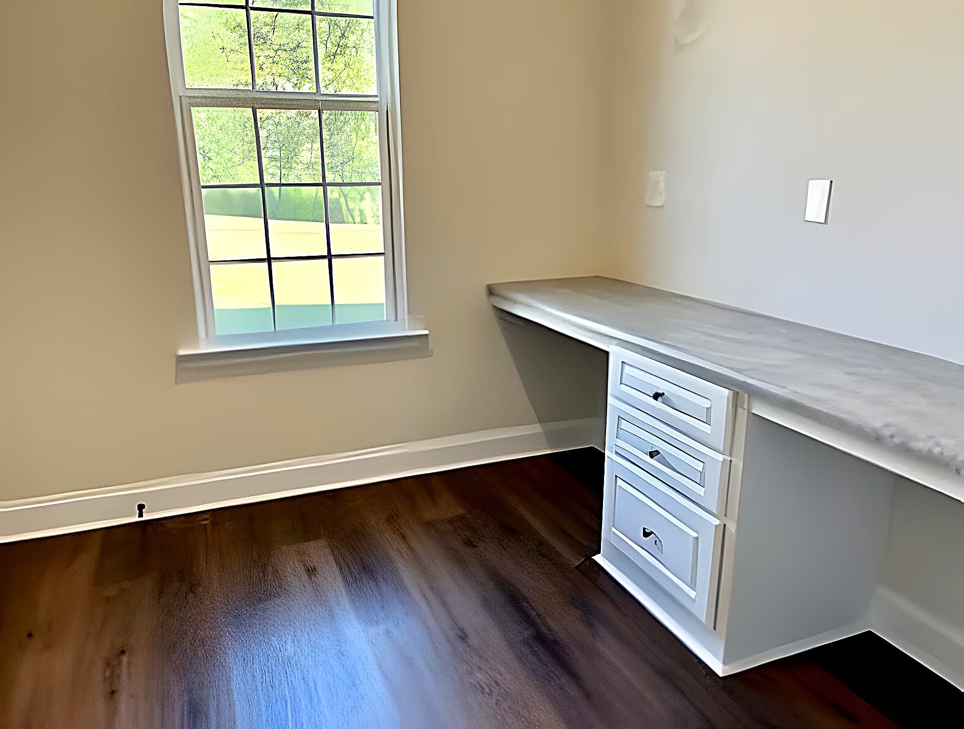 Home office with built-in desk and natural light from a large window