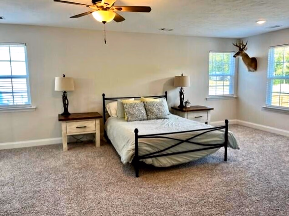 Spacious primary bedroom with ceiling fan and dual windows