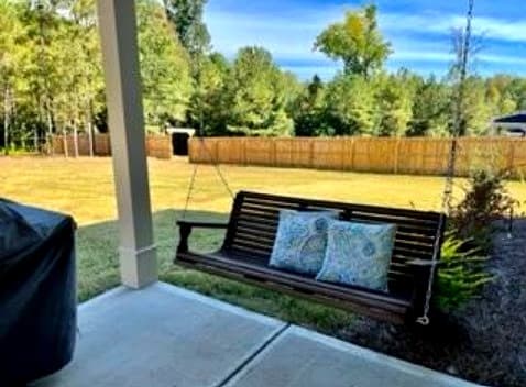 Covered back porch with swing overlooking the fenced backyard